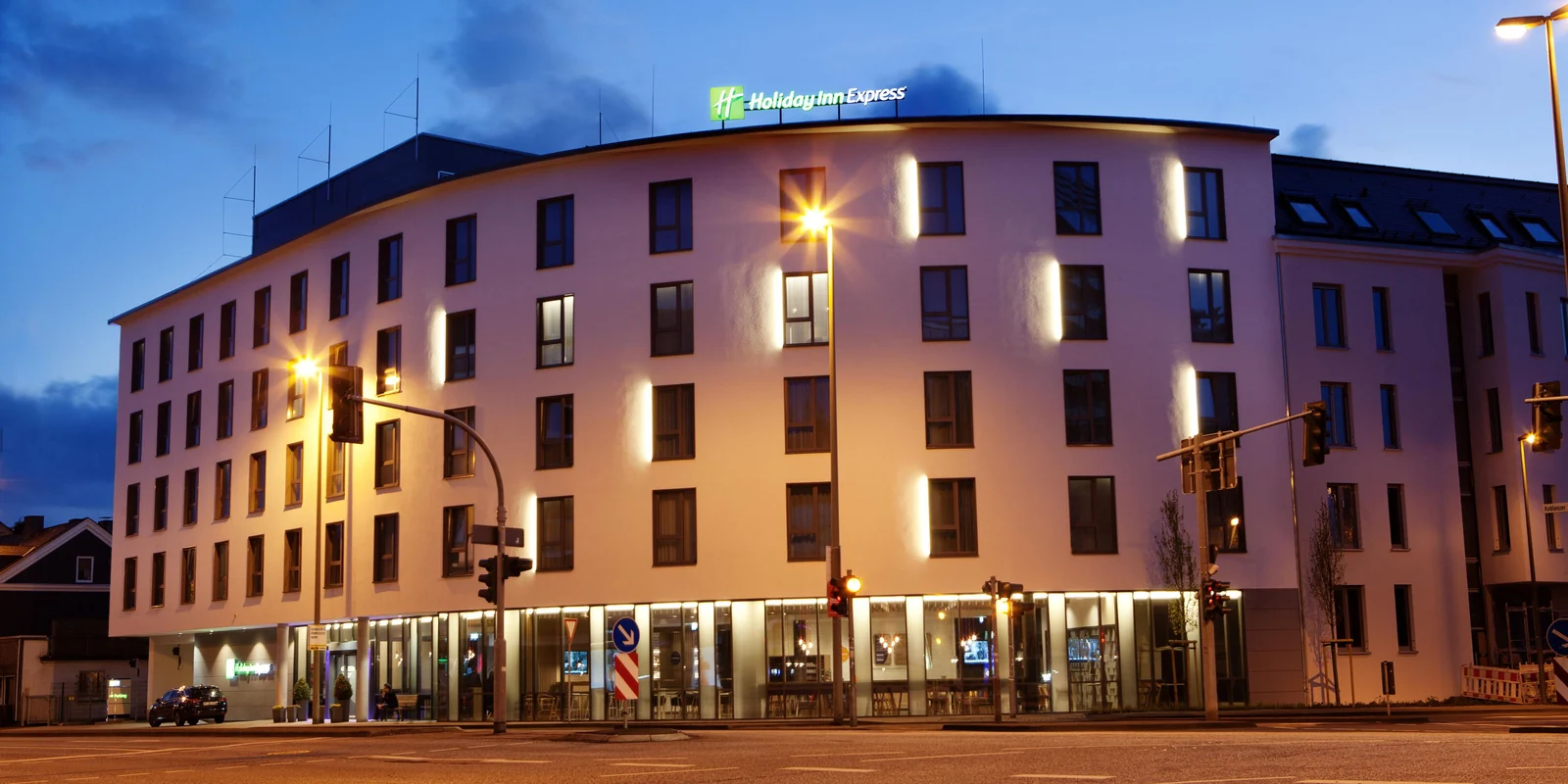 The illuminated Holiday Inn Express Siegen facade in the evening, with the entrance on the ground floor